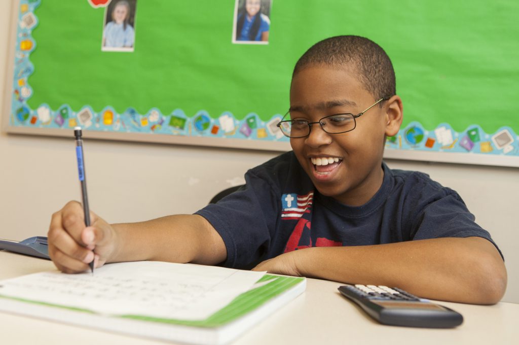 Smiling student writing at his desk