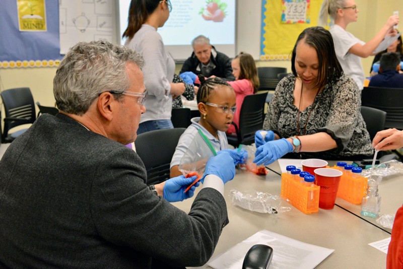 AstraZeneca’s Ruud Dobber (left) extracts DNA from strawberries with a family at the Delaware Biotechnology Institute’s Family STEAM Night