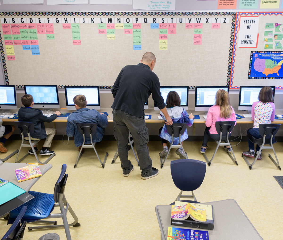 Teacher assists students with computer assignment at The College School