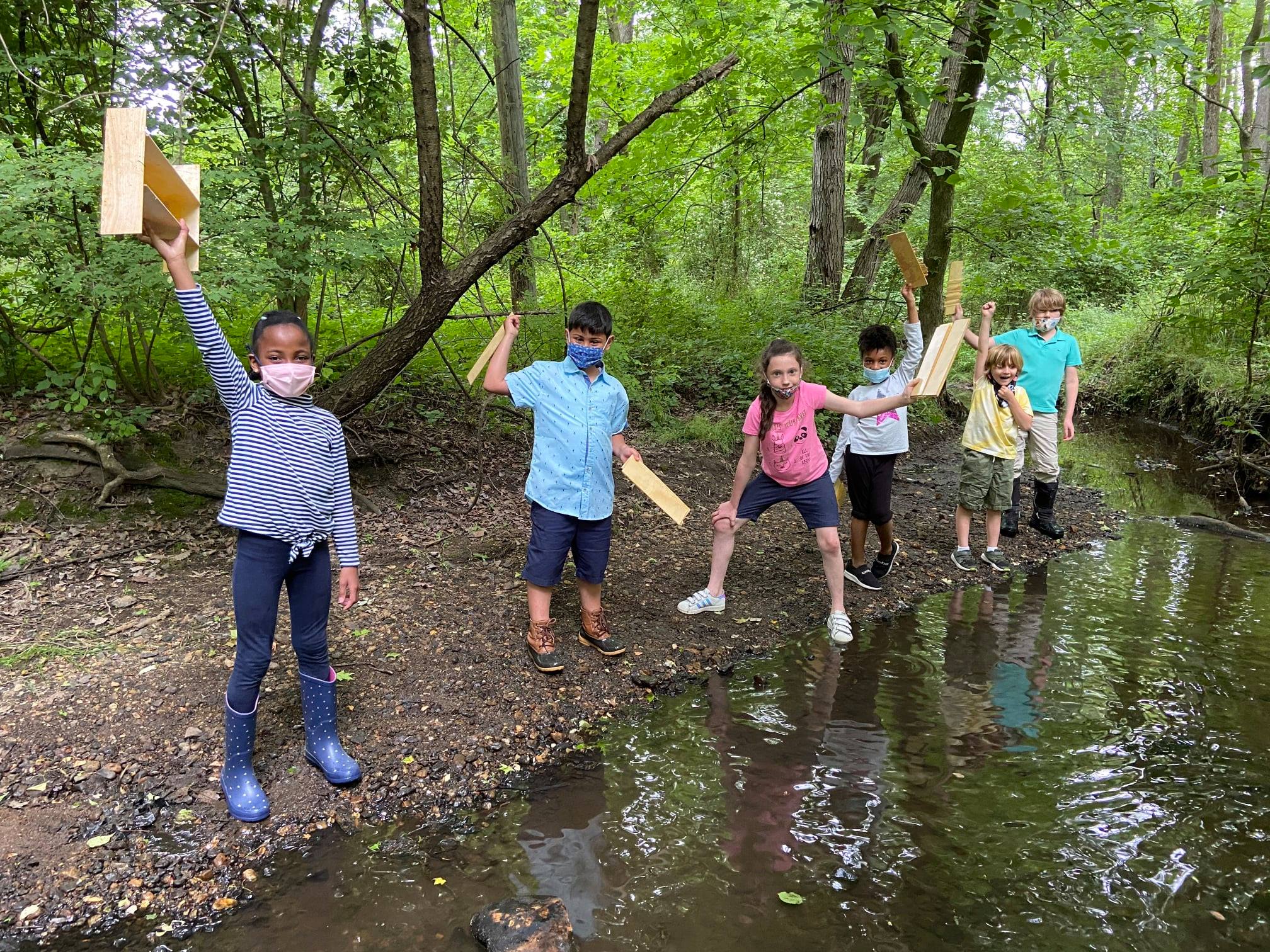 Masked students performing outdoot science experiment