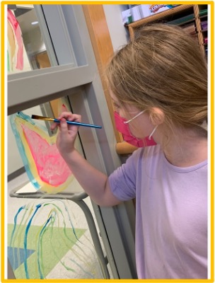 A student painting on a window at The College School